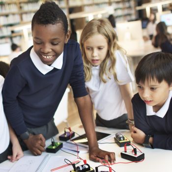 Three children in a classroom do an experiment