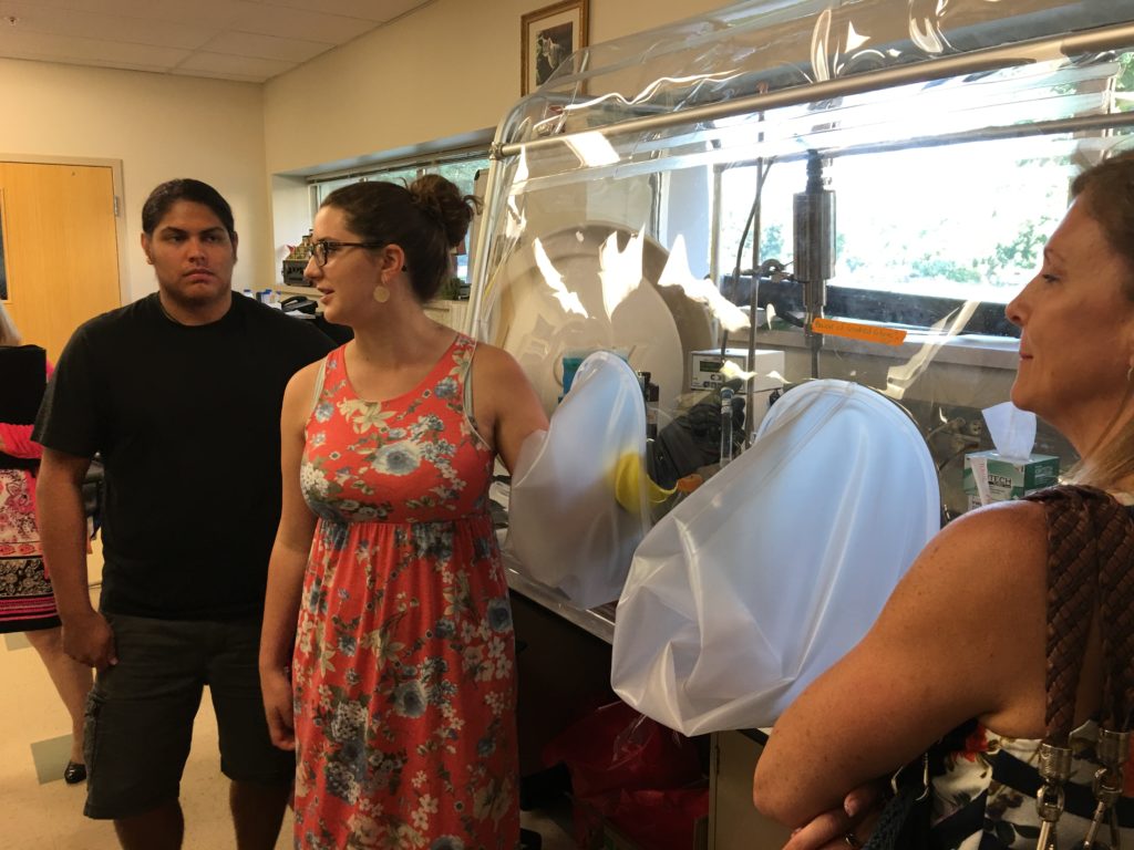 A woman wearing a floral dress demonstrates something inside a lab at Gonzaga University.