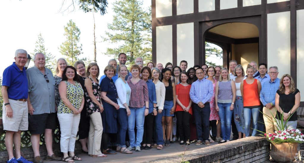 The Murdock Trust staff pose for a picture in front of a brown and white building.