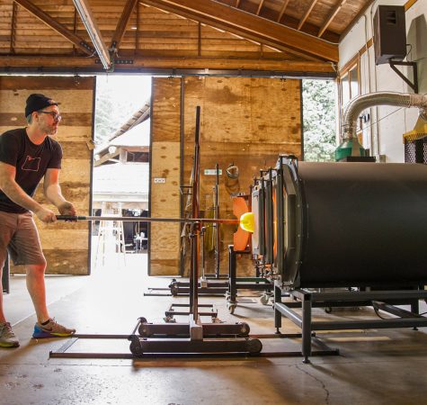 A student uses an energy-efficient, modular-designed gloryhole for reheating molten glass.