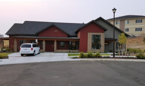 A building with dark red walls with a white van parked in front of it.