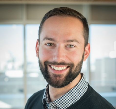 A man with dark hair and a beard smiling at the camera.