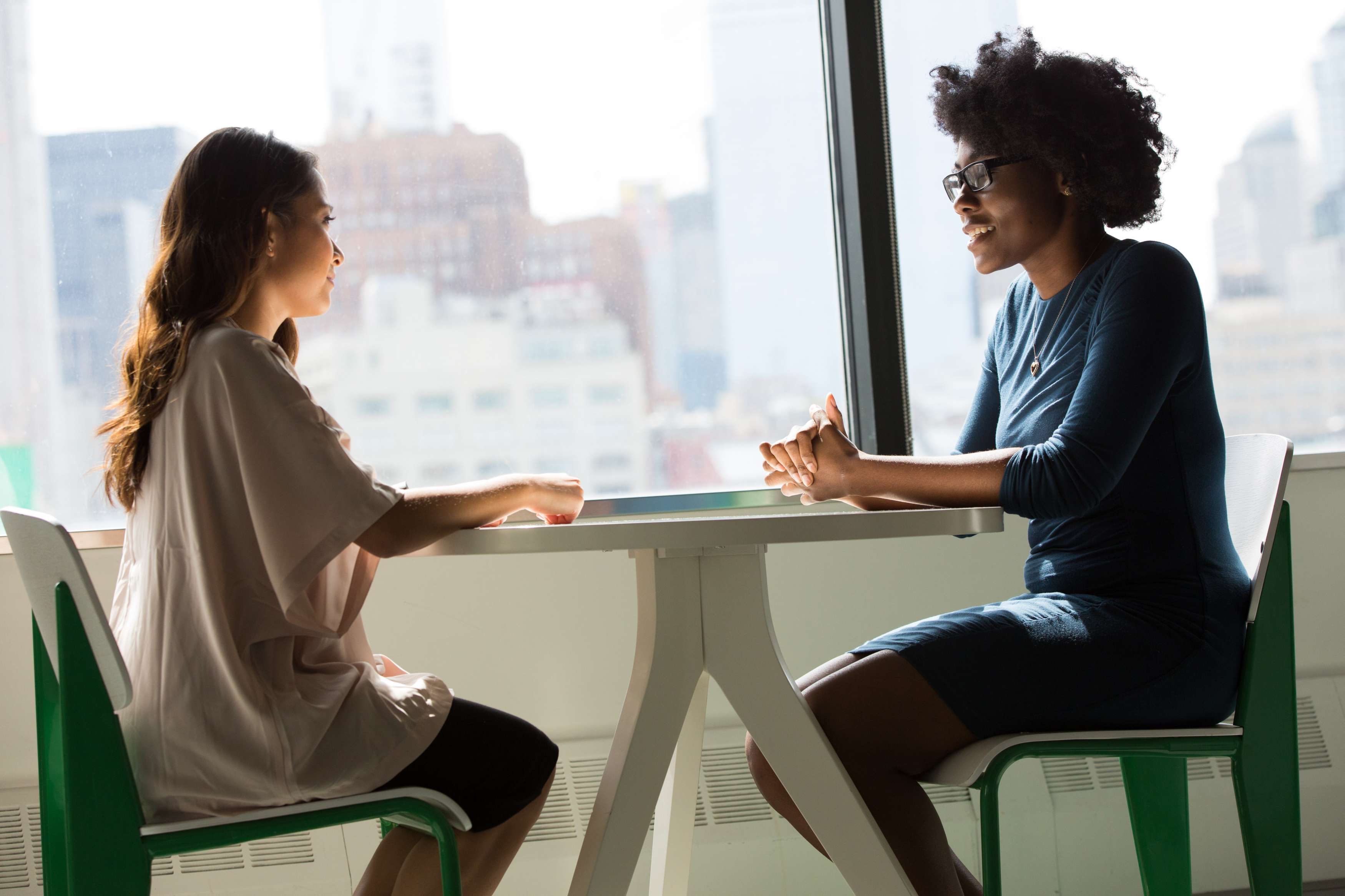 Two women have a conversation across a table.