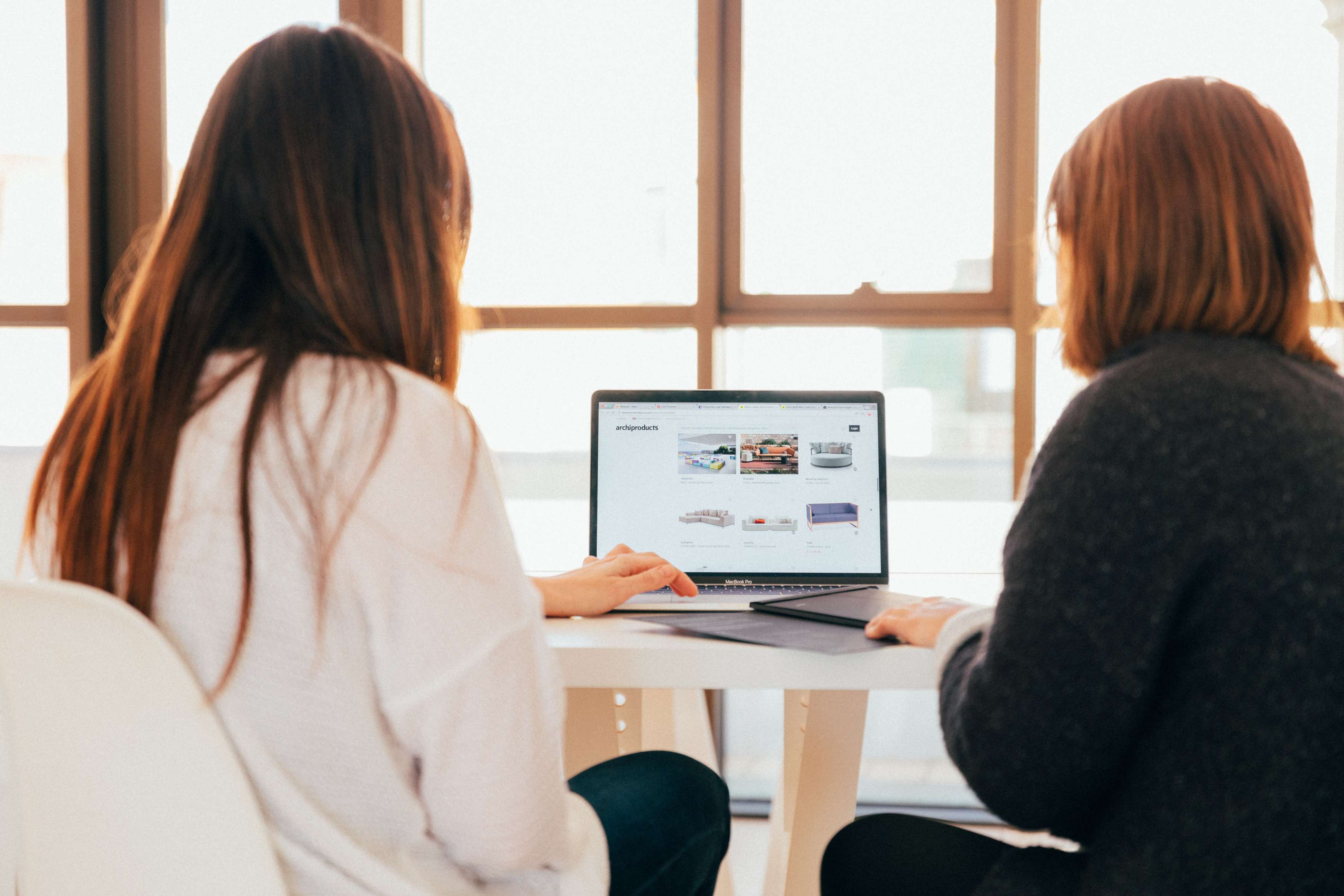 Two women look at a laptop together.