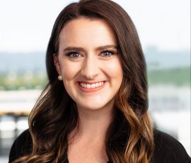 A woman with long dark hair smiles for the camera.