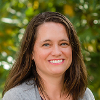 A 2022 Swanson Promise Award winner, Dr. Margaret Metz, a woman with straight dark hair smiling in front of trees.