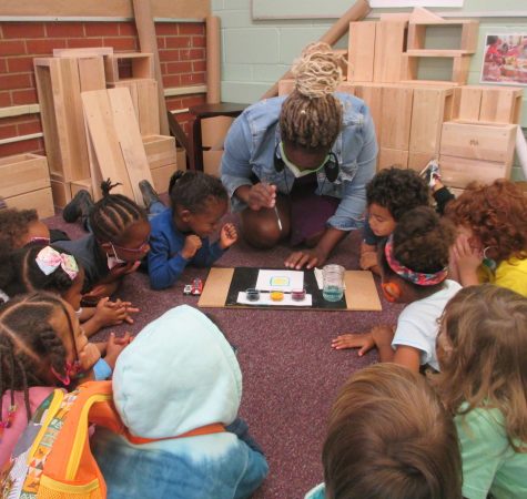 A group of students at KairosPDX gather around a teacher on the floor of a classroom.