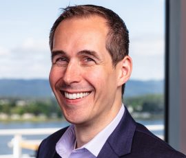 A man with dark hair wearing a suit smiles for the camera.