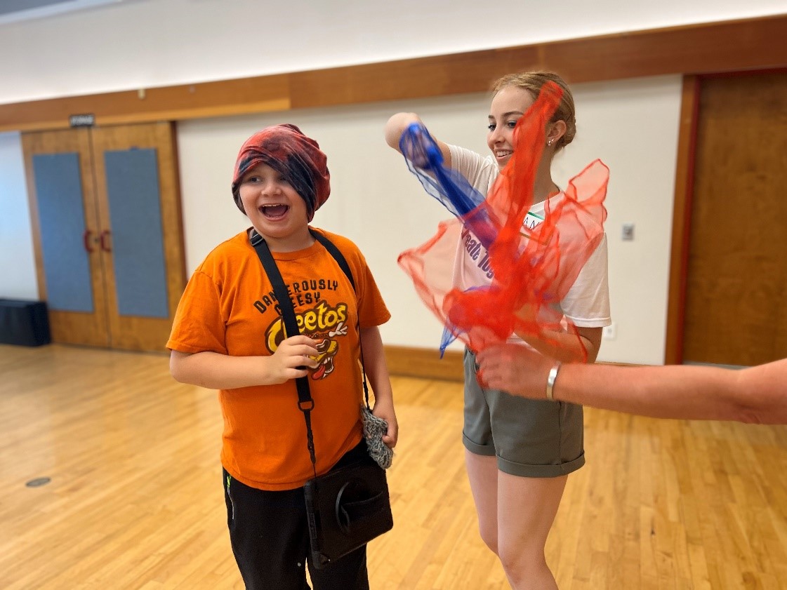 Young adult and child with colorful scarves inside a dance studio