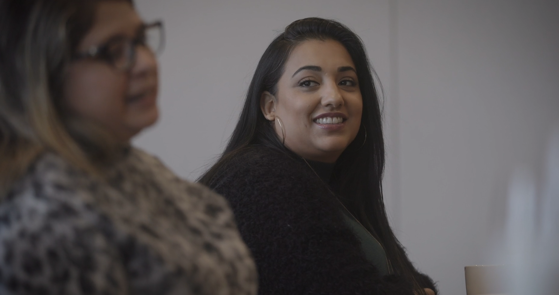 Woman smiling and listening as another woman talks