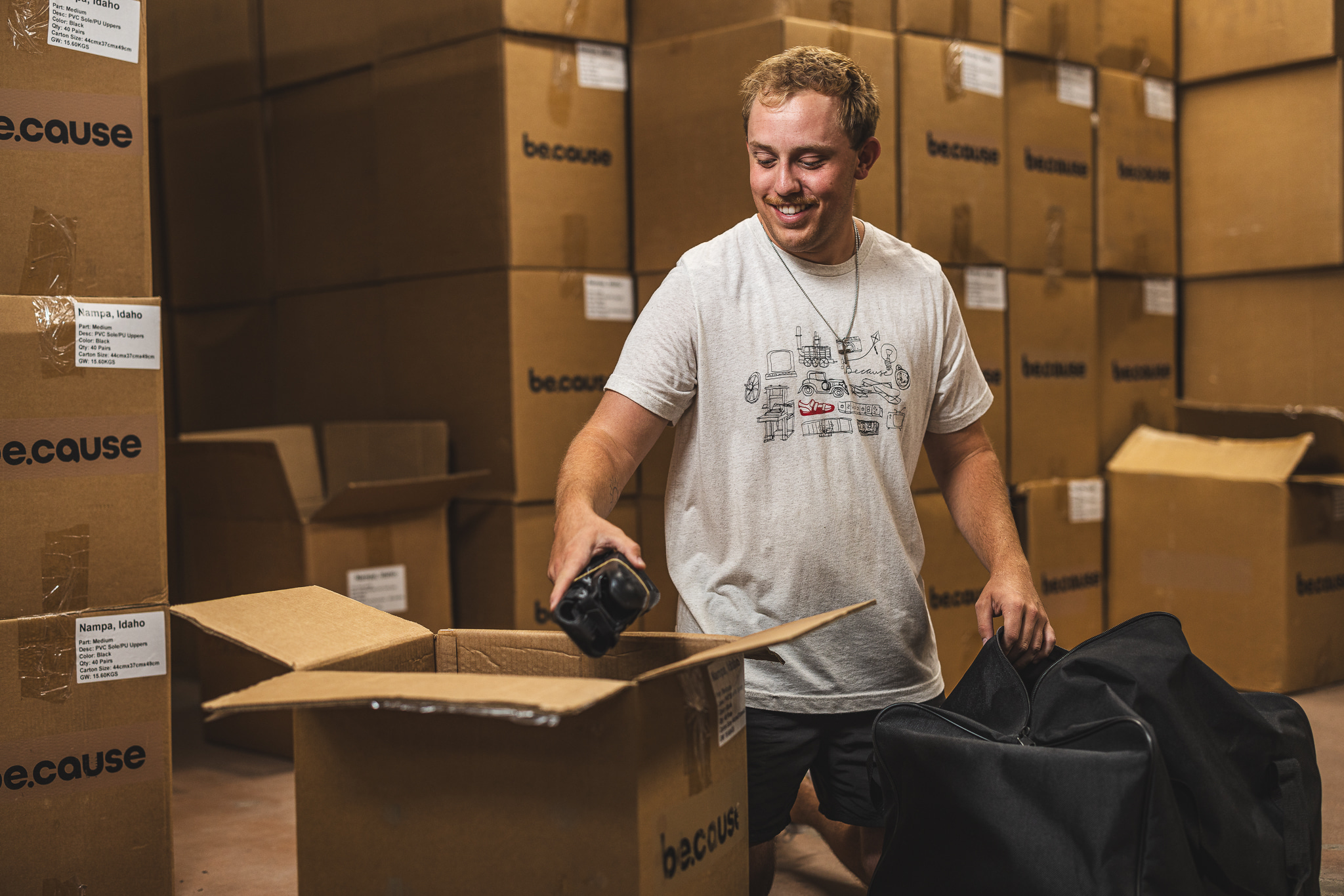 Young man scanning boxes in warehouse full of cardboard boxes