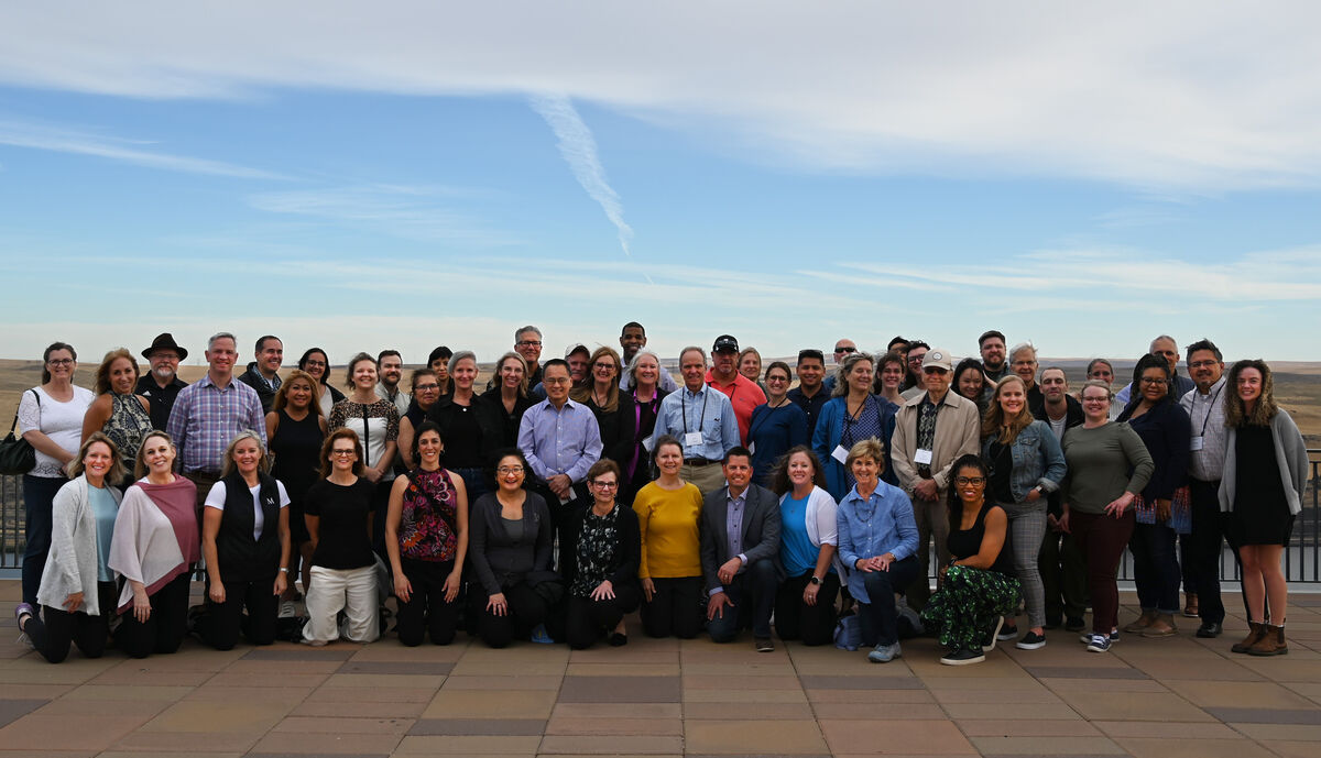 Group of people standing and kneeling in an outdoor area against a blue clear sky.